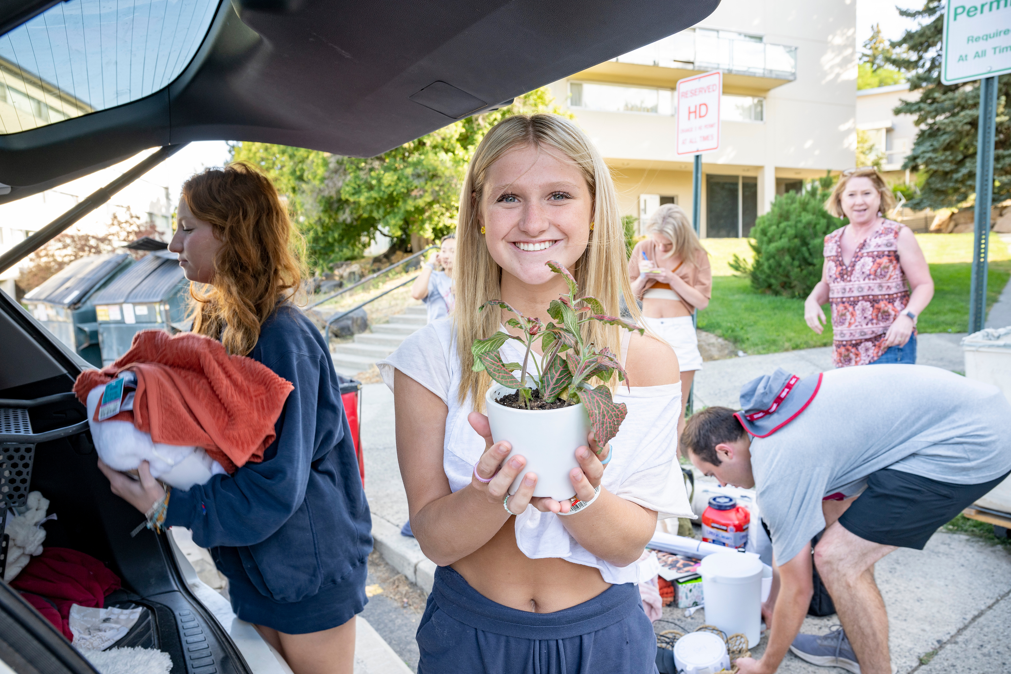 a student smiles and holds a plant on move in day